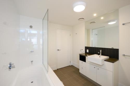 a white bathroom with a sink and a shower at Curtis Central Apartments Official in Gladstone