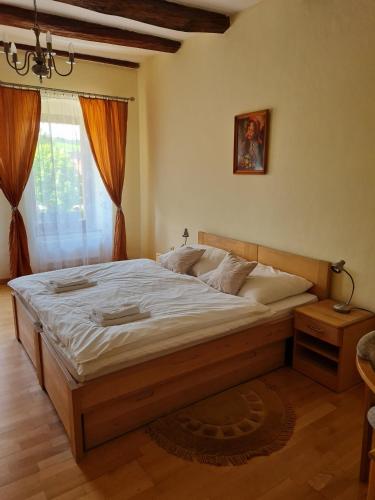 um quarto com uma grande cama de madeira em frente a uma janela em Andrišov dom penzion em Tvarožná