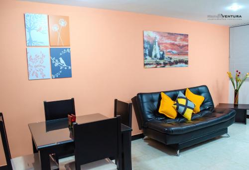 een woonkamer met een zwarte leren bank en gele kussens bij Apartamento Faunaventura cerca Parque del Café con piscina in Montenegro