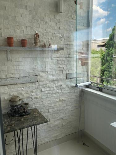 ein Badezimmer mit einer weißen Ziegelwand und einem Tisch in der Unterkunft Artistic Luxury in Skopje