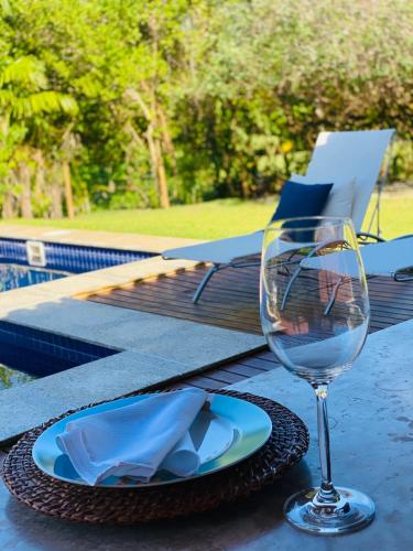 a glass of wine sitting on a table with a plate at Costa do Sauipe Casa dentro do complexo hoteleiro in Costa do Sauipe