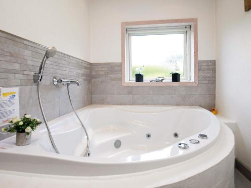 a white bath tub in a bathroom with a window at 8 person holiday home in Bl vand in Blåvand