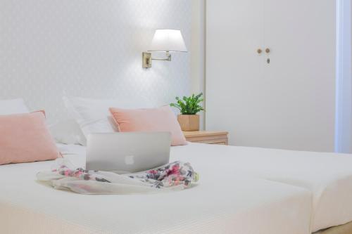 
a white bed sitting in a bedroom next to a lamp at Delice Hotel - Family Apartments in Athens
