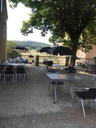 eine Gruppe von Tischen und Stühlen mit Sonnenschirmen in der Unterkunft Auberge de la fontaine aux loups in Saint-Sulpice-le-Dunois