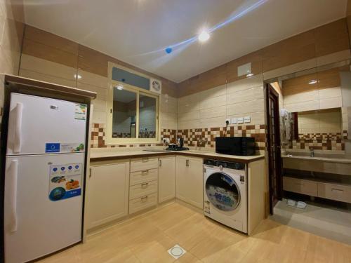 a kitchen with a refrigerator and a washing machine at Quartz Executive in Abha