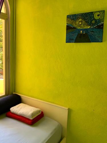 um quarto amarelo com uma cama e uma janela em Room 4 rent em San Salvador