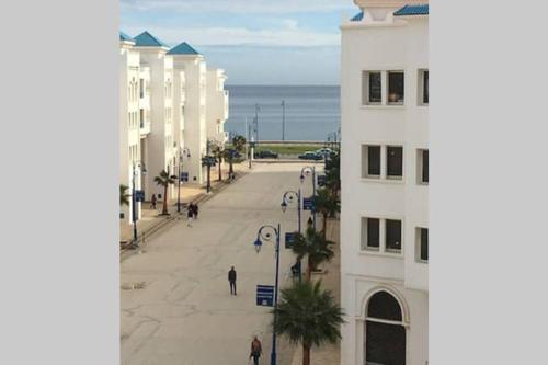 a view of a street with a white building and the ocean at Magnifique appartement a louer à fnideq avec parking gratuit in Fnidek