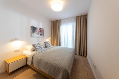 een slaapkamer met een bed en een raam bij Apartamenty BALTIVIA Olimpijska 2 in Mielno