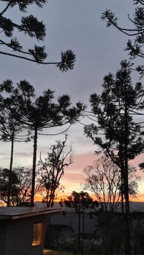 a view of a sunset from a house with trees at Sunset Serrano Chalés in Urubici