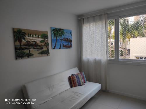 a white living room with a couch and a window at Lindo apartamento ao lado do Park Shopping Canoas in Canoas
