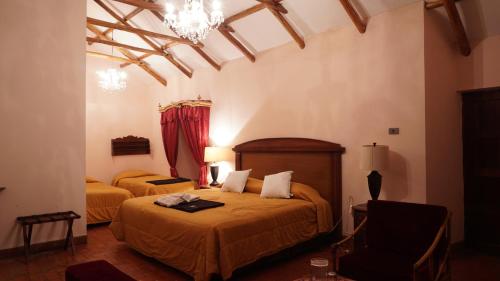 a bedroom with two beds and a chair and a chandelier at Hotel Museo Cayara in Santa Lucía