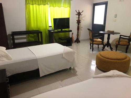 a bedroom with a bed and a tv and chairs at Hotel El Lago in Puerto Carreño