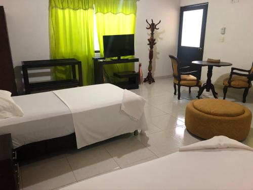 a bedroom with a bed and a tv and chairs at Hotel El Lago 