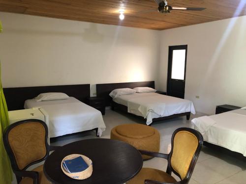 Habitación de hotel con 2 camas, mesa y sillas en Hotel El Lago, 