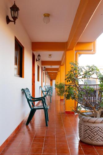 a corridor of a building with green chairs and plants at Casablanca Hotel Tula in Tula de Allende