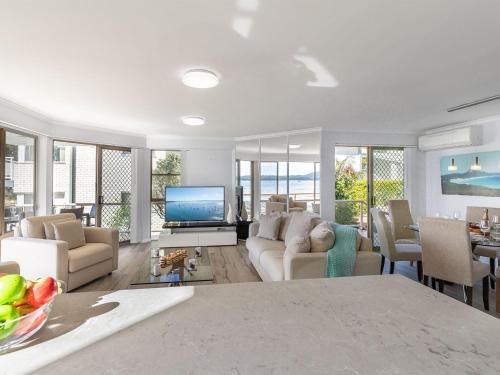 a living room with a couch and a tv at Pelican Sands 2 fantastic waterfront unit with pool and air conditioning in Soldiers Point