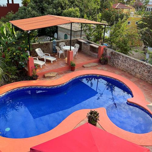 a large swimming pool with a table and a umbrella at Casa Monarca in Chacala