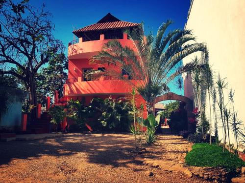 a red building with a palm tree in front of it at Casa Monarca in Chacala