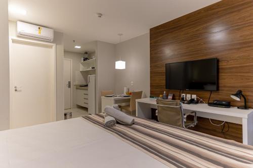 a bedroom with a bed and a desk and a tv at Vision otima localização vista incrível e muitas comodidades in Brasilia
