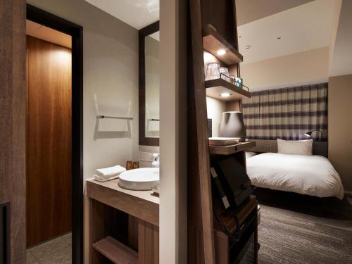 a bathroom with a sink and a bed in a room at Granbell hotel Tanuki, Sapporo in Sapporo