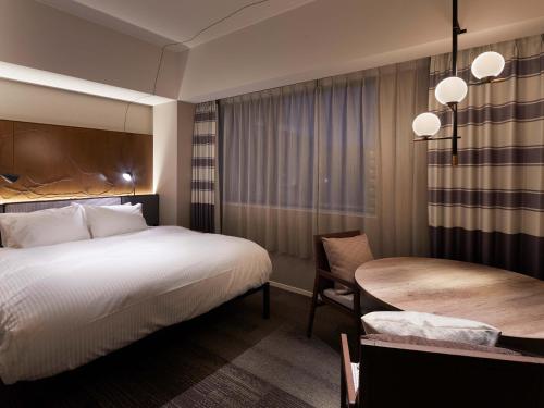 a hotel room with a bed and a table at Granbell hotel Tanuki, Sapporo in Sapporo