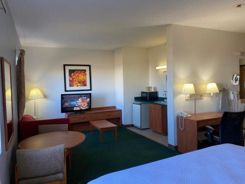 Habitación de hotel con cama, TV y mesa. en Carlyle Inn & Suites, en Carlyle