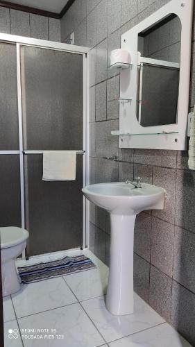 a bathroom with a sink and a shower with a mirror at Pousada Pier 123 in Penha