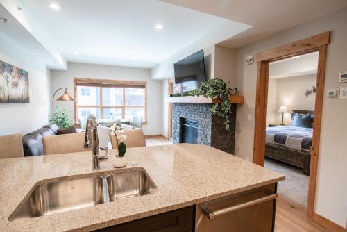 a kitchen with a sink and a living room at Spring Creek Luxury Queen Suite at White Spruce Lodge in Canmore