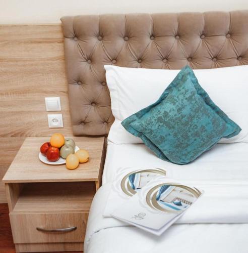 a bed with a tray of fruit on a table at Park Hotel al Bustan in Shymkent