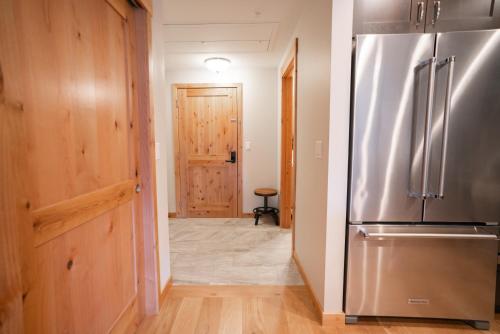 a hallway with a stainless steel refrigerator in a house at Spring Creek Serene Luxury at White Spruce Lodge in Canmore