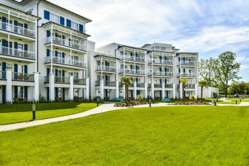a large white apartment building with a green lawn at BalaLake Resort in Szántód