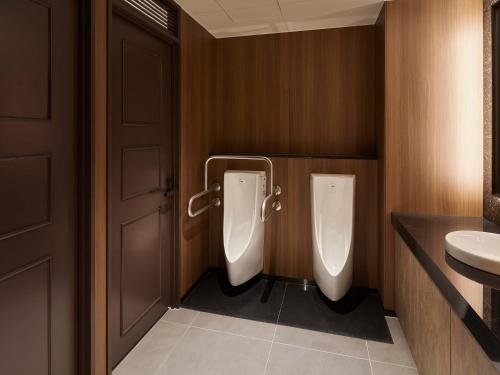a bathroom with two urinals and a sink at Granbell hotel Tanuki, Sapporo in Sapporo