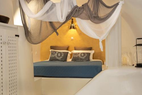 a bedroom with a bed with drapes on it at Villa Orpheus Santorini in Megalochori