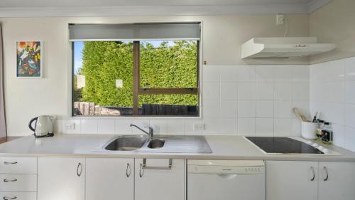 a white kitchen with a sink and a window at Kapiti Views - Waikanae Beach Holiday Home in Waikanae