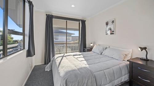 a bedroom with a bed and a large window at Kapiti Views - Waikanae Beach Holiday Home in Waikanae