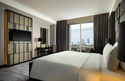 a bedroom with a large white bed and a large window at Grand Swiss-Belhotel Darmo in Surabaya