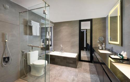 a bathroom with a toilet and a sink and a shower at Grand Swiss-Belhotel Darmo in Surabaya
