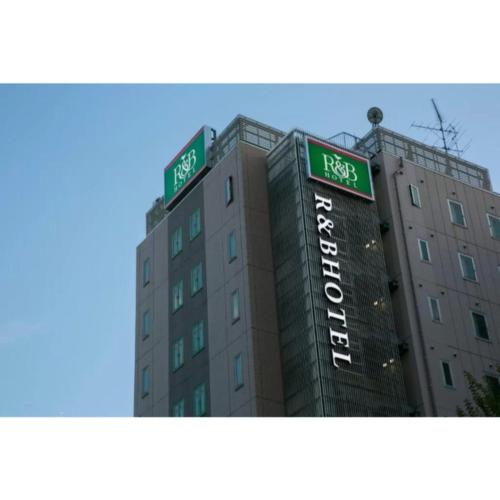 un edificio con dos letreros verdes encima en R&B Hotel Nagoya Nishiki - Vacation STAY 37481v, en Nagoya