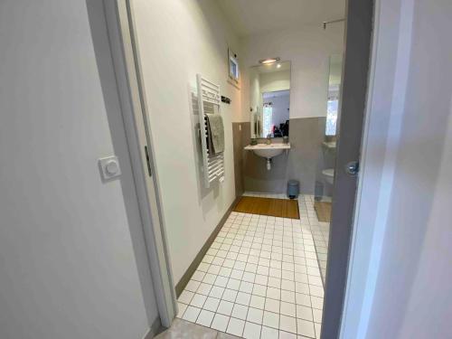 a bathroom with a sink and a white tiled floor at Chambre d'hôte au pied du Ventoux in Malaucène