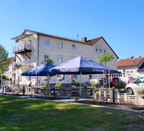 einen Tisch mit blauen Sonnenschirmen vor einem Gebäude in der Unterkunft Hotel Maurer in Saarwellingen