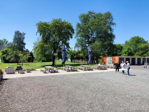 un groupe de personnes se promenant autour d'un parc avec des tables de pique-nique dans l'établissement Hotel Maurer, à Saarwellingen