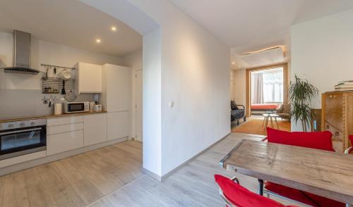 cocina y sala de estar con mesa de madera y sillas rojas en Lyves en Lieja