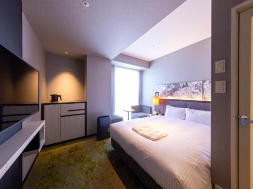 a bedroom with a large white bed and a window at Hotel Forza Kyoto Shijo Kawaramachi in Kyoto