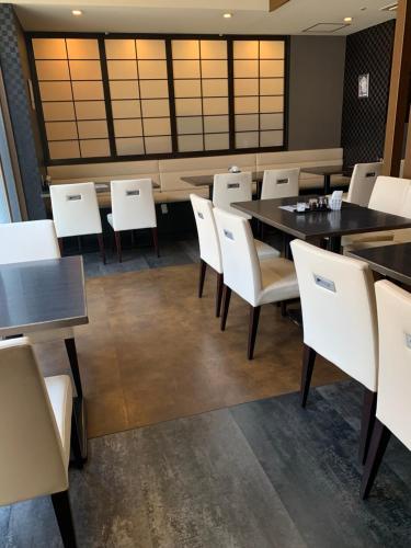 a dining room with white chairs and tables at Smile Hotel Nagoya Sakae in Nagoya