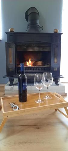 グラボヴァツにあるHouse Anitaの暖炉の前のテーブルの上に置かれたワイングラス2杯とボトル1本