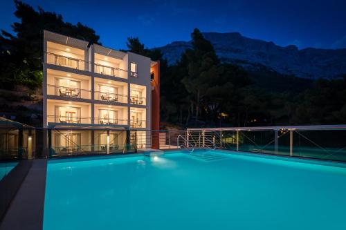 a building with a swimming pool at night at Noemia Apartments in Baška Voda