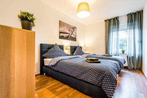 Schlafzimmer mit einem Bett mit blauer und weißer Bettwäsche in der Unterkunft Comodo Apartments Solingen in Solingen