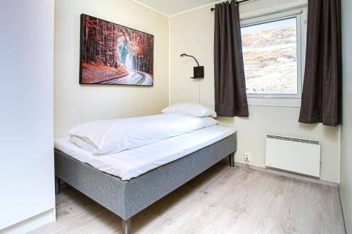1 cama en una habitación con una foto en la pared en Easy Home Apartments en Hammerfest