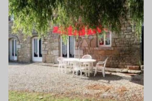 a table and chairs in front of a building at appartement 4 pers dans longère à 800m de la plage in Plouhinec