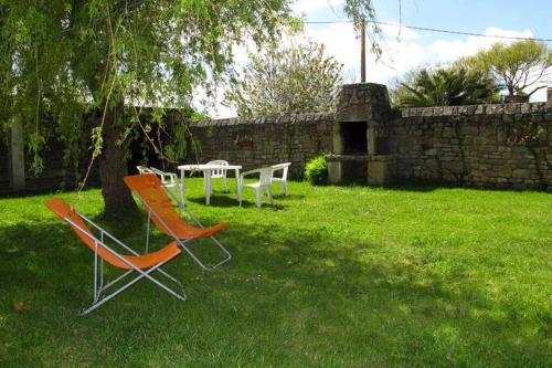 two chairs and a table in a yard at appartement 4 pers dans longère à 800m de la plage in Plouhinec